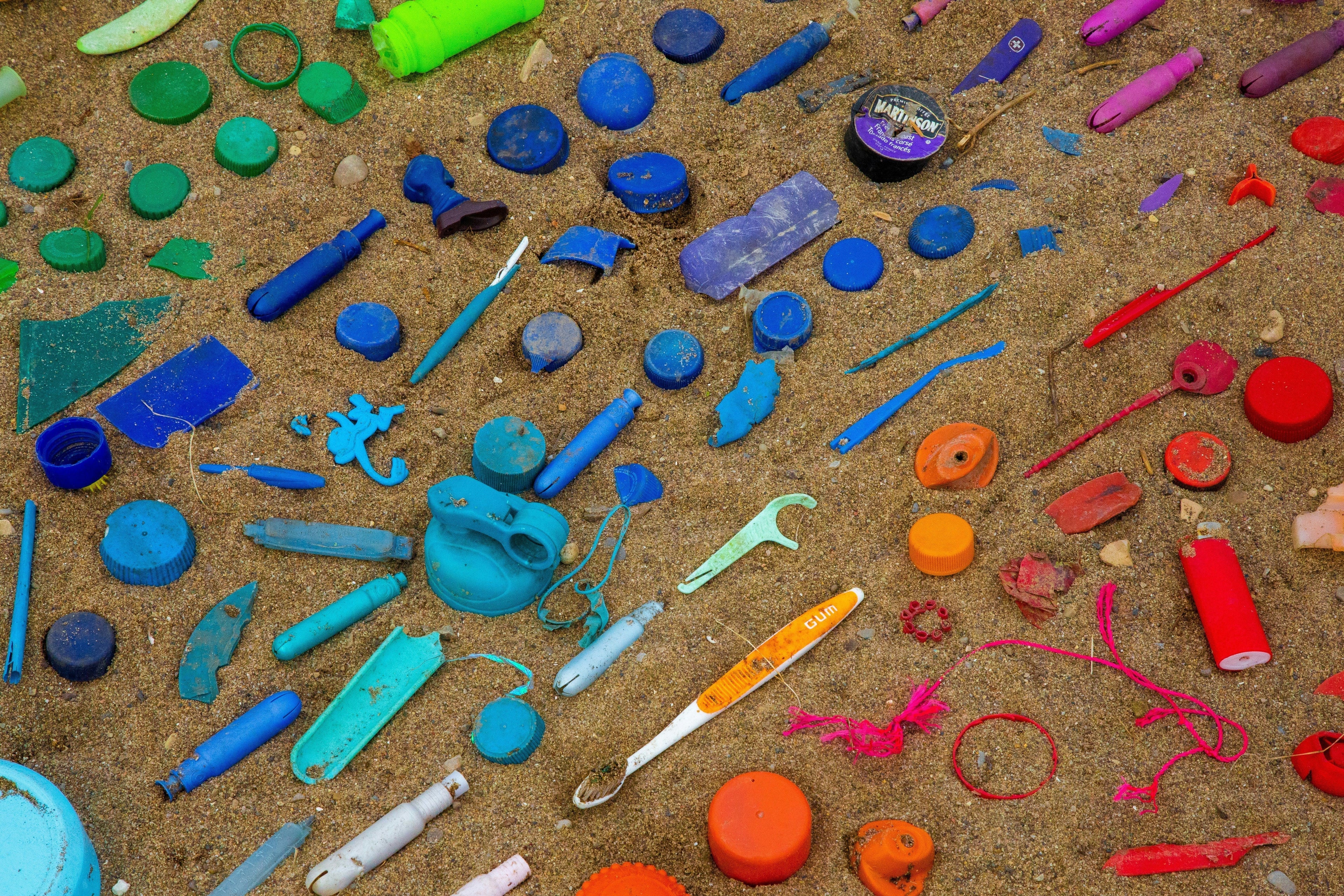 Plastic on the beach, laid out in a rainbow pattern.