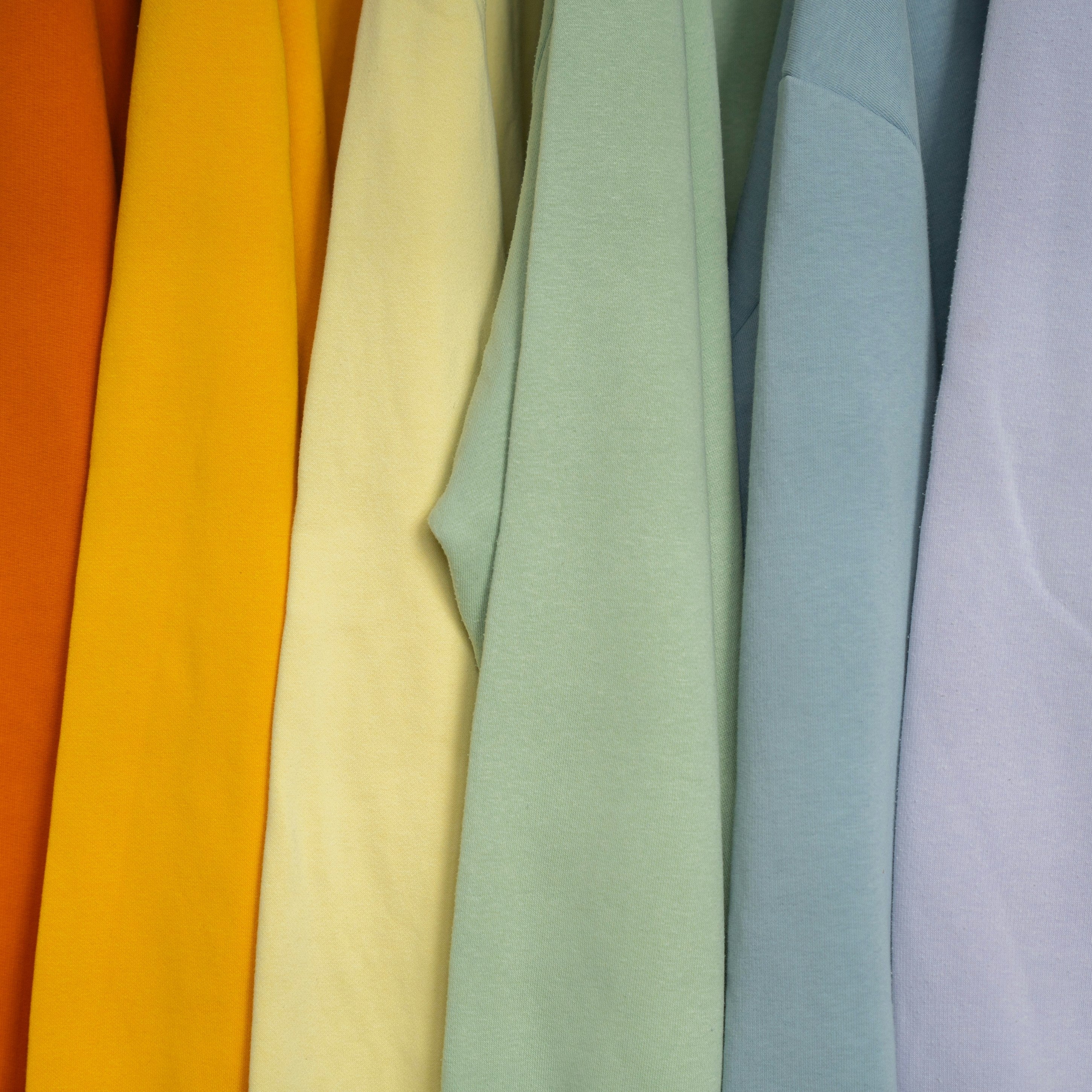 Colorful sweaters hanging on a rack.