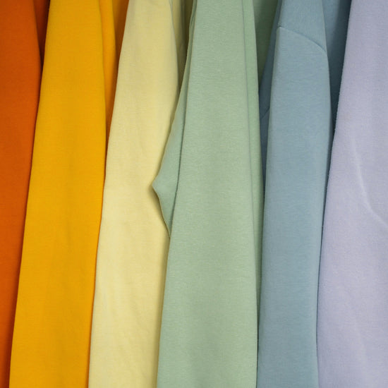 Colorful sweaters hanging on a rack.