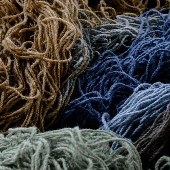 A messy pile of natural earthy tone yarns.